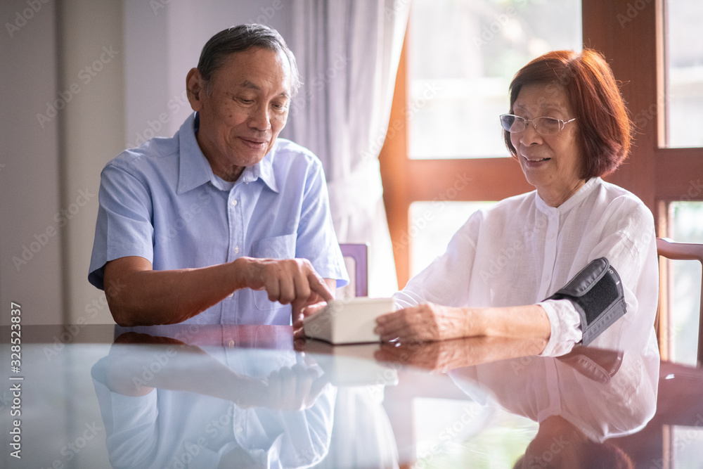 Asian retired couple operate home blood pressure monitoring